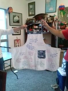 two people standing in front of a white dress with writing on it