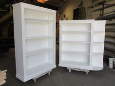 two white bookcases sitting next to each other in a garage with tools on the floor