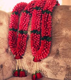 red flowers and pearls are arranged on the back of a couch