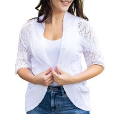 a woman in jeans and a white top is holding her hands together while smiling at the camera