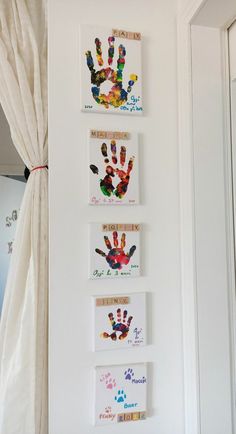 three handprints are hung on the wall in front of a window with curtains