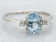 an oval cut blue topaz ring with three diamonds on the sides and side stones