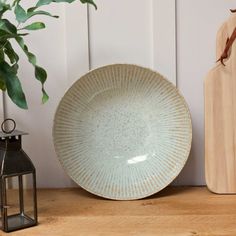 a white plate sitting on top of a wooden table next to a potted plant