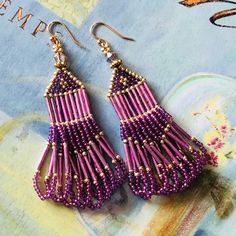 purple beaded fringe earrings on top of a blue and white book with gold trimmings