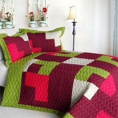 a bed with a red and green bedspread on it next to two lamps