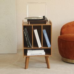 a record player sitting on top of a wooden shelf next to a chair and ottoman