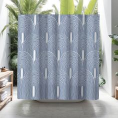 a shower curtain with an abstract design in blue and white, next to a potted plant