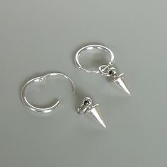 A PAIR of sterling silver hoops. Comes with a detachable spike charm. The charm is multipurpose and can be used with a neck or bracelet chain too. Dimension: Hoop- 1.2 x 12 mm Spike charm: 5 x 9 mm Weight: 1.6 gm Price is for ONE PAIR. These earrings are made of 925 hypoallergenic sterling silver. Most of my pieces come with a 925 stamp. Can be packaged in a gift box. I can include a personal message from you if needed You are welcome to contact me at... bhavnakwintra1956@gmail.com For more beau Trendy Silver Earrings With Charms, Silver Minimalist Huggie Earrings With Charms, Silver Dangle Huggie Earrings With Charms, Silver Dangle Hoop Earrings With Charms, Silver Punk Hoop Earrings Gift, Small Silver Punk Hoop Earrings, Silver Sterling Silver Charm Hoop Earrings, Punk Style Small Hoop Nickel-free Earrings, Punk Sterling Silver Nickel-free Hoop Earrings