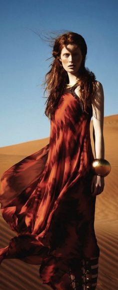 a woman in a red dress is standing in the desert