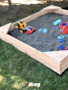 an empty sandbox with toys in it on the grass