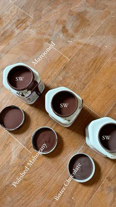 six cups of coffee sitting on top of a wooden floor next to the names of each cup