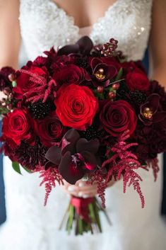 a bride holding a bouquet of red flowers