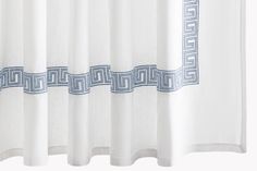 a white shower curtain with blue greek border