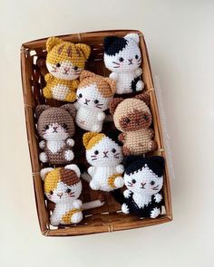 a basket filled with small crocheted cats sitting on top of a table