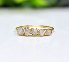 a yellow gold ring with five white diamonds on the top and bottom, sitting on a table