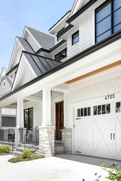 a white house with two garage doors and windows