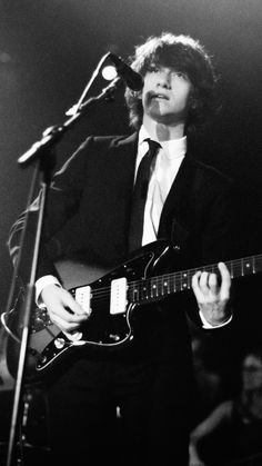 a man in a suit and tie playing an electric guitar while singing into a microphone