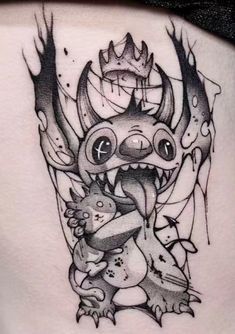 a woman's lower back tattoo with an image of a monster holding a baby