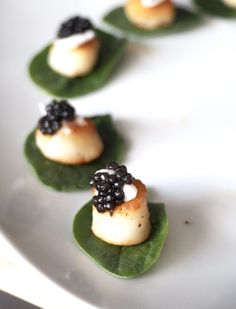 small appetizers are arranged on top of green leaves