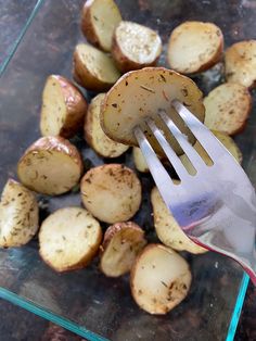 a fork is being used to cut potatoes into small pieces and put them in a glass dish