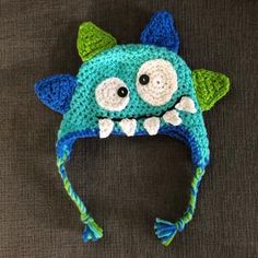 a crocheted blue and green monster hat with big eyes