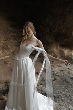 a woman in a white dress standing on rocks