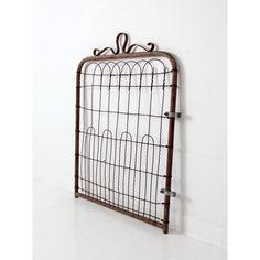 a decorative iron wall hanging on the side of a white wall with two hooks attached to it