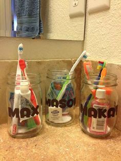 three jars with toothbrushes in them sitting on a counter