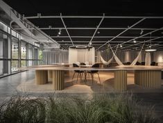 an empty conference room with tables and chairs in the center, surrounded by tall grass