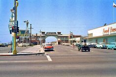 cars are driving down the street in front of a building with an arch above it