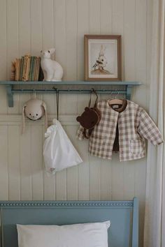 a baby's room with white walls and blue bedding, stuffed animals on the wall