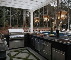 an outdoor kitchen with grill, sink and seating area