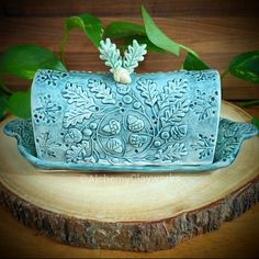 a decorative blue box sitting on top of a wooden table next to green leaves and flowers