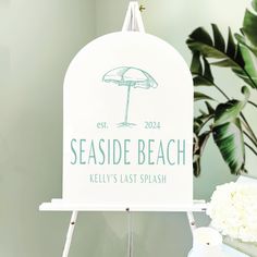 there is a sign that says seasidee beach and an umbrella next to flowers on the table