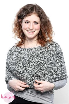 a woman with curly hair is smiling and posing for the camera while wearing a black and white sweater