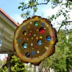 a piece of wood with different colored glass beads hanging from it's center, in front of a house