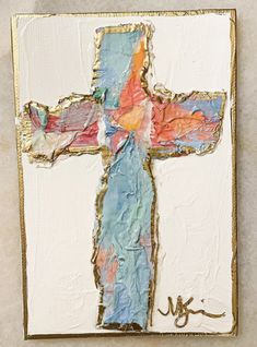 a cross made out of colored paper on a white surface with gold trimmings