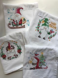 four embroidered christmas napkins with santa and snowmen on them