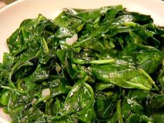 a white bowl filled with green vegetables on top of a table