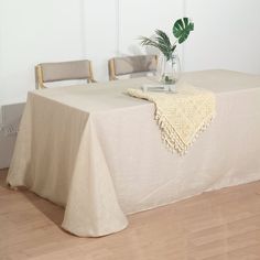 a table with a white cloth on it and a plant in a vase next to it