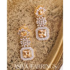 An exquisite testament to refined luxury! Meticulously crafted to exude opulence, these earrings glistens with an ethereal brilliance of CZ and champagne stones. Approximate earrings length is 2.1". Gold-plated on high quality brass as base metal. Made by order. Kindly allow 5-7 weeks for the delivery of this item. For custom or urgent requests, please contact support@alacouture.com. *Please Note: We use faux stones and beads in all of our jewelry. Exquisite Crystal Drop Earrings, Evening Hand Set Cubic Zirconia Earrings, Hand Set Cubic Zirconia Evening Earrings, Hand Set Cubic Zirconia Earrings For Evening, Luxury Bridal Drop Earrings With Sparkling Stones, Exquisite Diamond Chandelier Earrings In Gold, Formal Drop Cluster Earrings With Sparkling Stones, Luxury Earrings With Sparkling Stones For Wedding, Glamorous Cubic Zirconia Earrings With Diamond Accents