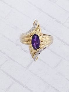 Vintage Amethyst & Diamond ring. Details: Size: US 6 1/2 ( Can be sized ) Weight: 4.4 grams Primary stone: Amethyst Stone Shape: Marquise ( Appx. 10mm x 5mm ) Secondary Stone: Diamond Stone Shape: Round Metal: 14k Yellow Gold Condition: Brand new Inside of band is stamped and tested for '14k' gold. SIZING: Currently this ring is a size 6 1/2 but could be sized up or down for an additional small fee if desired by adding custom ring sizing to your cart upon checkout. Most sizing can be done wi Formal Purple Diamond Ring With Gemstone Accents, Amethyst Ring In Yellow Gold With Diamond Accents, Yellow Gold Amethyst Ring With Diamond Accents, Elegant Purple Multi-stone Diamond Ring, 14k Gold Purple Ring With Diamond Accents, Purple Gemstone Diamond Ring In 14k Gold, Purple Multi-stone Amethyst Ring In Fine Jewelry Style, Purple Diamond Amethyst Ring With Multi-stone, Formal Amethyst Diamond Ring With Gemstone Accents