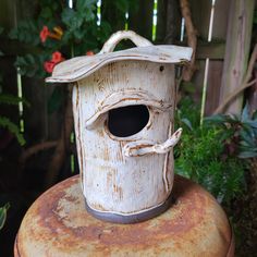 a bird house sitting on top of an old rusty barrel