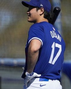 a baseball player holding a bat on top of his shoulder and wearing a blue uniform