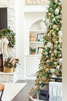 a living room decorated for christmas with green and gold ornaments on the tree, fireplace mantel