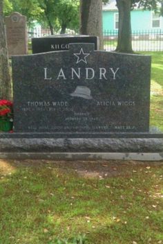 a headstone in the middle of a cemetery with red flowers on it's grave