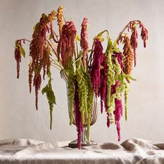 some very pretty flowers in a glass vase on a cloth tablecloth with white background