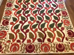 a large red and green rug on the floor in front of a wooden flooring