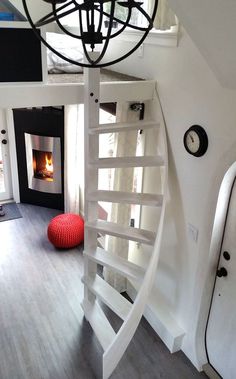 a spiral staircase leading up to a fire place in a room with white walls and wood floors