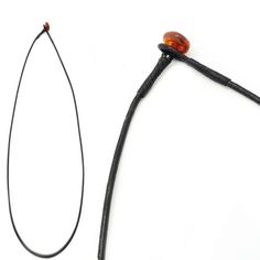 an orange bead hangs from the side of a black leather cord, next to a piece of metal wire